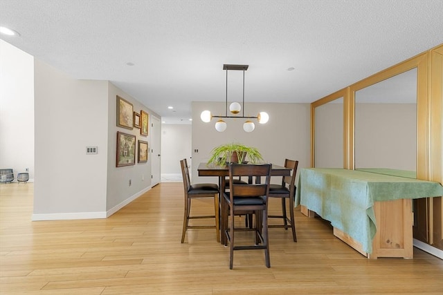 dining room with recessed lighting, light wood-style floors, baseboards, and a textured ceiling