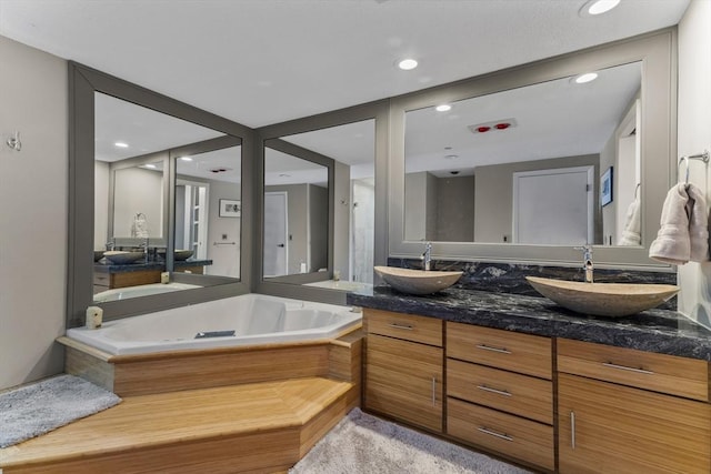 full bathroom featuring a sink, recessed lighting, a bath, and double vanity