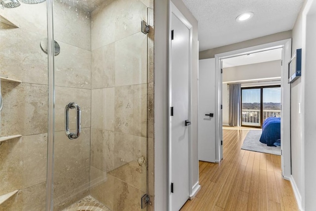 bathroom with a textured ceiling, wood finished floors, and a shower stall