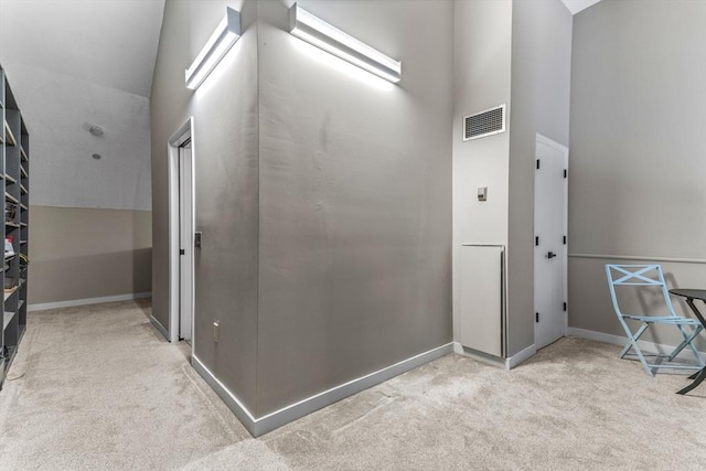 corridor featuring visible vents, a high ceiling, baseboards, and carpet floors