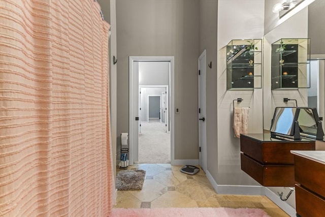 bathroom with baseboards, vanity, and a towering ceiling