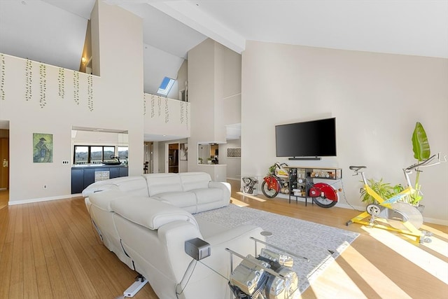 living room featuring beamed ceiling, high vaulted ceiling, baseboards, and wood finished floors