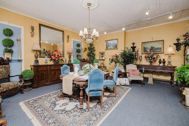 carpeted dining room with an inviting chandelier, track lighting, and crown molding
