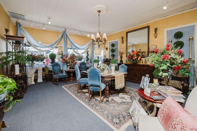 carpeted dining space featuring rail lighting, an inviting chandelier, and visible vents
