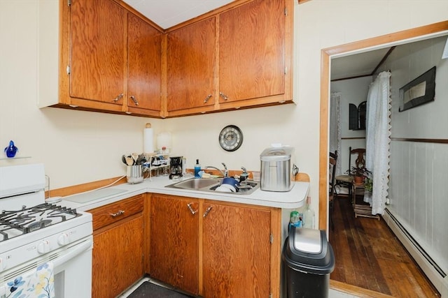 kitchen with white gas range, brown cabinetry, light countertops, a sink, and a baseboard heating unit