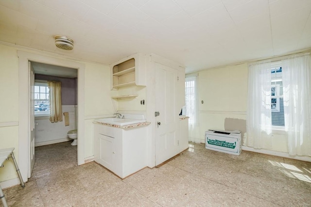 kitchen featuring light countertops, open shelves, white cabinetry, and a sink