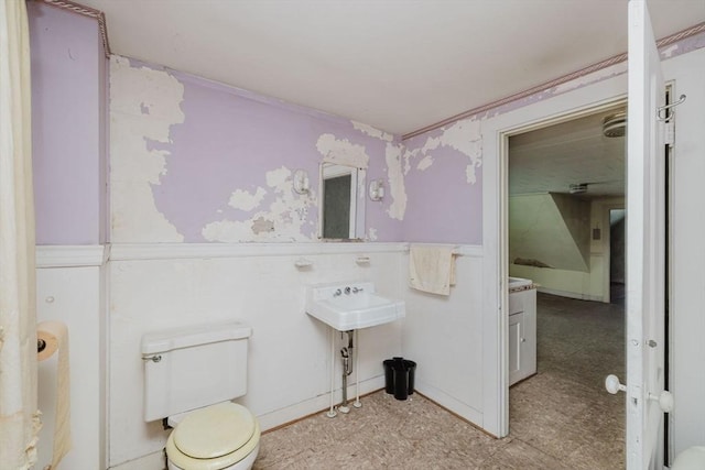 bathroom featuring wainscoting, a decorative wall, toilet, wallpapered walls, and tile patterned floors
