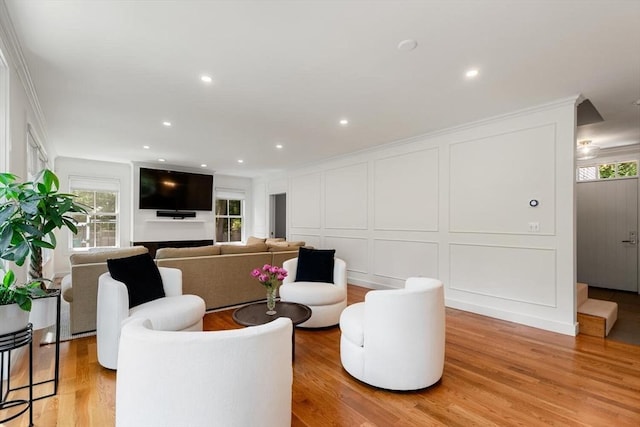 living room featuring recessed lighting, a decorative wall, and light wood-style flooring