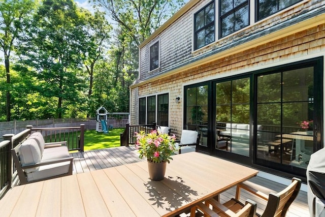 wooden deck with outdoor dining area, a lawn, and fence