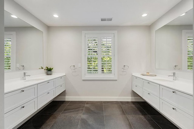 full bathroom with visible vents, two vanities, baseboards, and a sink