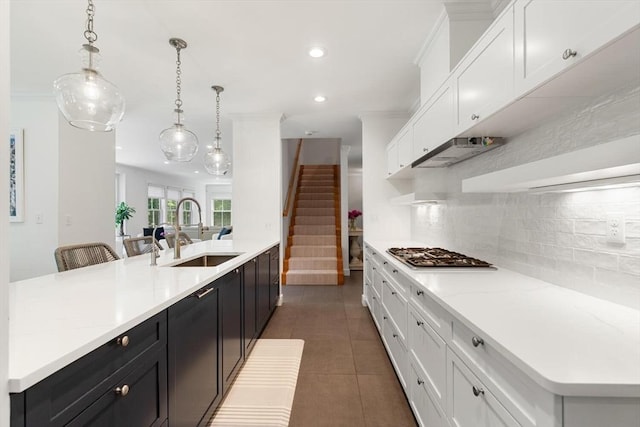 kitchen featuring a sink, stainless steel gas cooktop, decorative backsplash, white cabinets, and dark cabinets