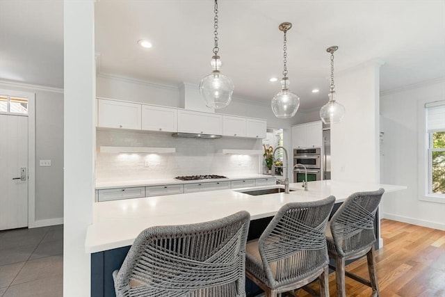 kitchen featuring crown molding, a kitchen breakfast bar, appliances with stainless steel finishes, and a sink