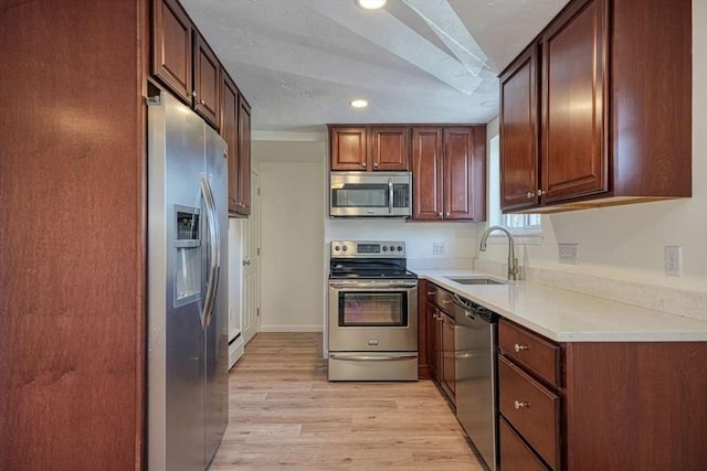 kitchen featuring light countertops, light wood-type flooring, recessed lighting, appliances with stainless steel finishes, and a sink