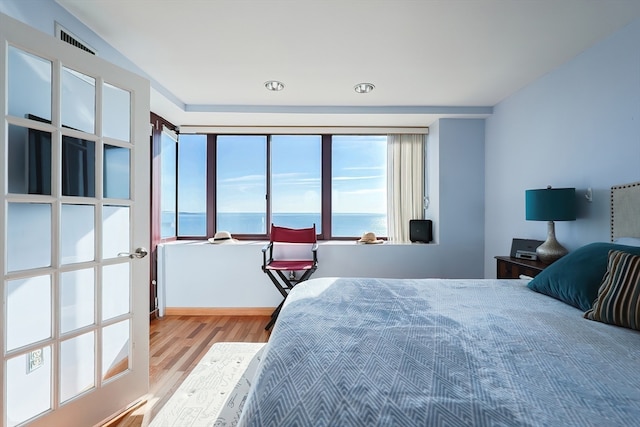 bedroom featuring a water view and light wood-type flooring