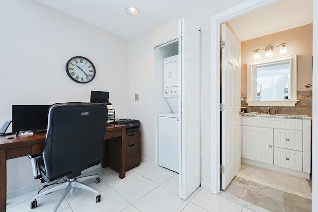 office with light tile patterned floors, sink, and stacked washer and clothes dryer