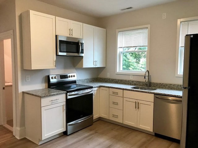 36-38 Coleman St, Boston, MA 02125 - kitchen featuring stainless steel appliances, light wood finished floors, white cabinetry, and light stone countertops