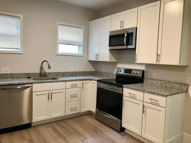 36-38 Coleman St, Boston, MA 02125 - kitchen with appliances with stainless steel finishes, light wood-style floors, white cabinetry, and light stone counters
