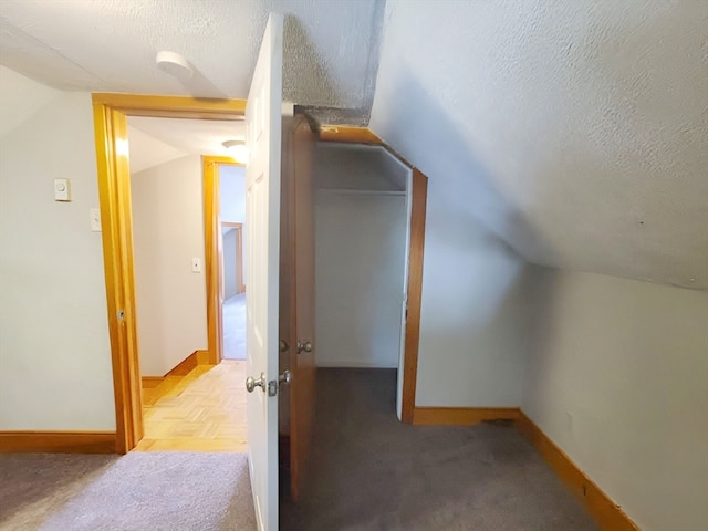 additional living space with a textured ceiling and vaulted ceiling