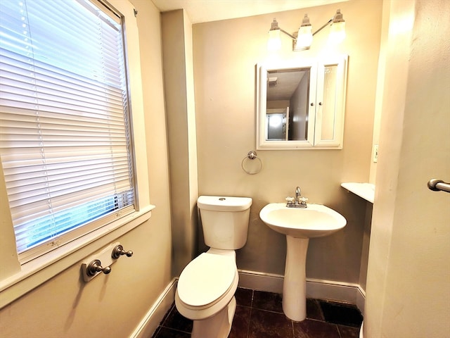 bathroom with toilet, plenty of natural light, and tile patterned flooring