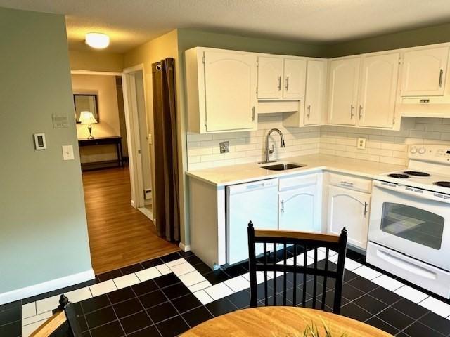 kitchen with sink, dark wood-type flooring, tasteful backsplash, white appliances, and white cabinets