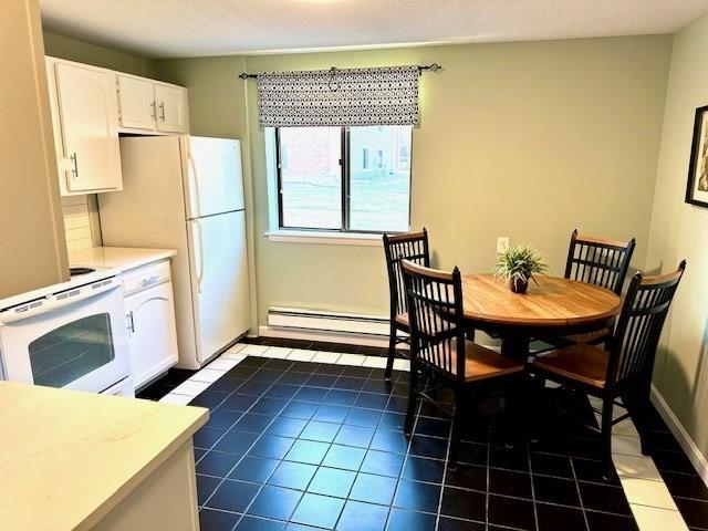 kitchen with dark tile patterned flooring, white range, white cabinetry, and a baseboard heating unit