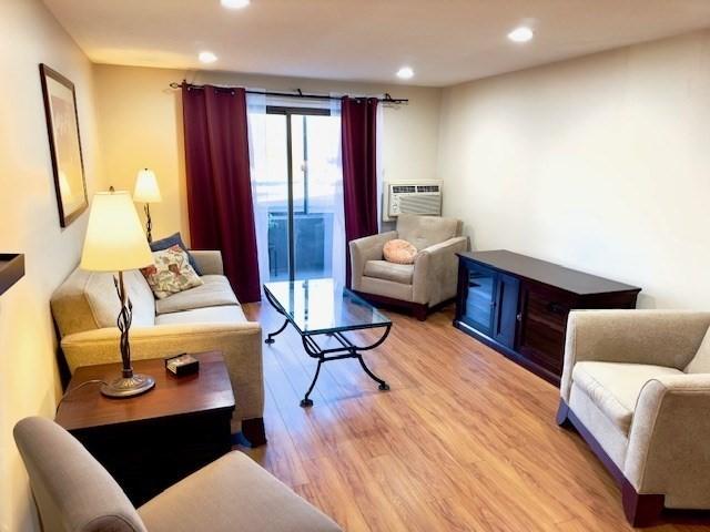 living room featuring an AC wall unit and light hardwood / wood-style flooring