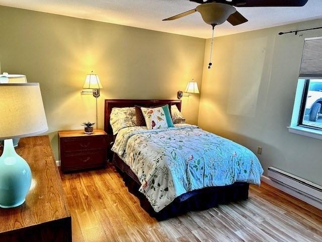 bedroom with a baseboard radiator, light hardwood / wood-style flooring, and ceiling fan