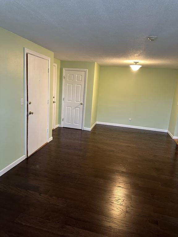 unfurnished room featuring dark wood finished floors, a textured ceiling, and baseboards