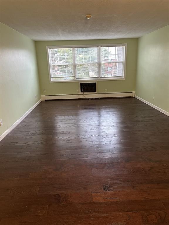 spare room with dark wood-style floors and baseboards