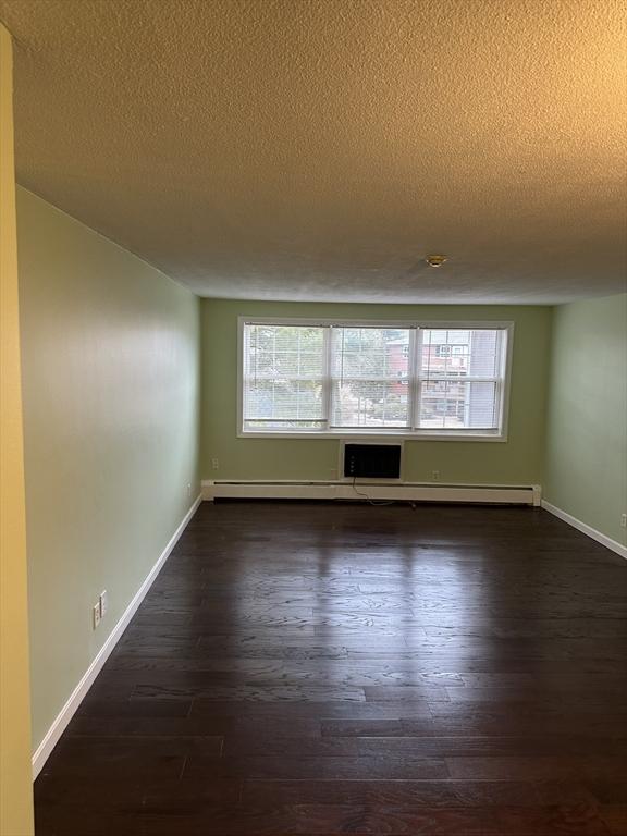 empty room with dark wood-style flooring, plenty of natural light, and baseboards