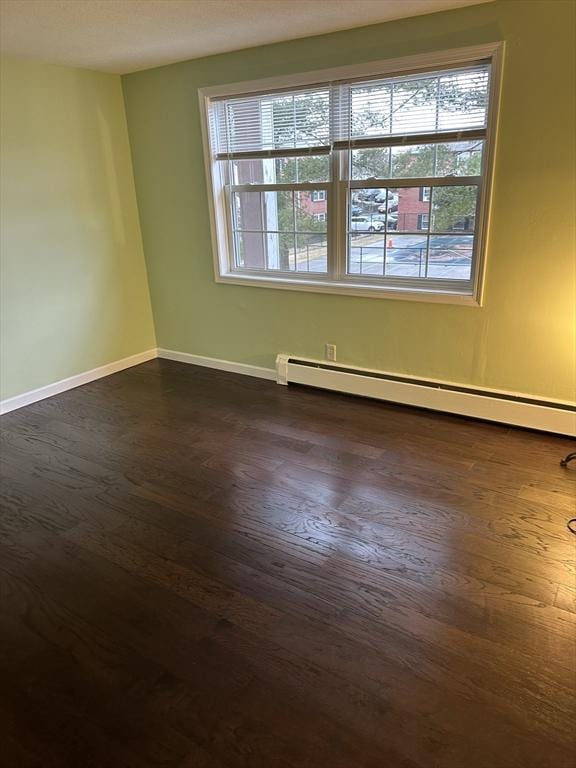 spare room with a baseboard radiator, dark wood finished floors, and baseboards