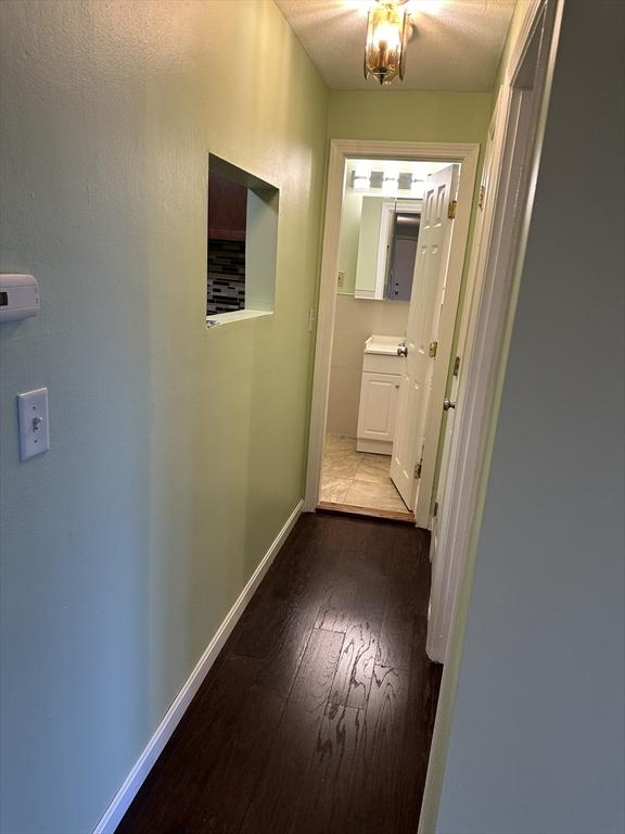 hallway with dark wood-style flooring and baseboards