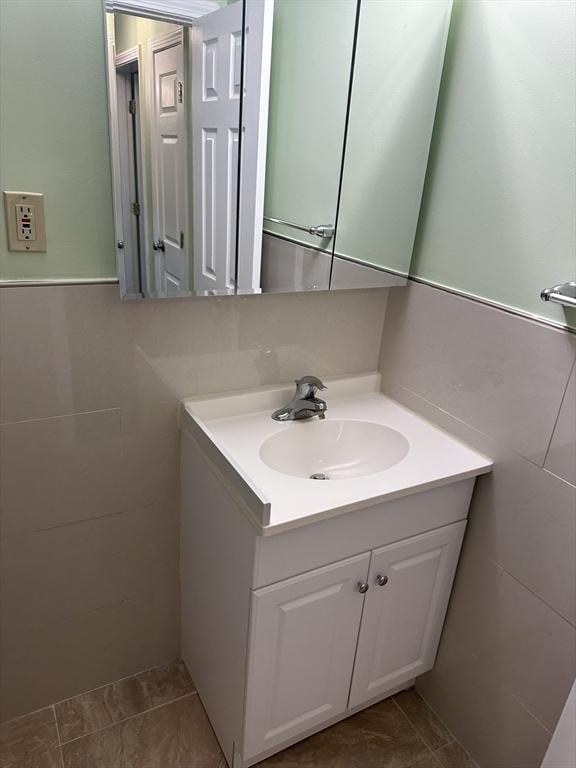 bathroom with tile patterned flooring, vanity, and tile walls