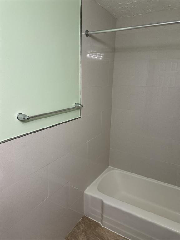 full bathroom with shower / tub combination and tile walls