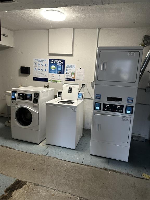 community laundry room with a textured ceiling, washer and clothes dryer, and stacked washer / drying machine