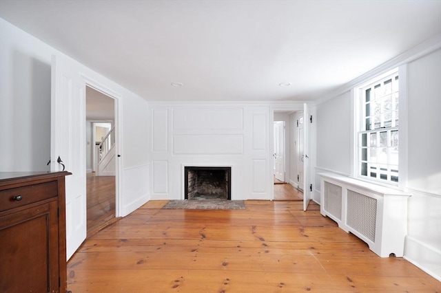 unfurnished living room featuring radiator, crown molding, and light hardwood / wood-style flooring