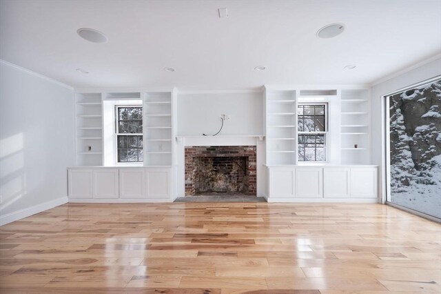 unfurnished living room with light hardwood / wood-style flooring, built in features, crown molding, and a fireplace