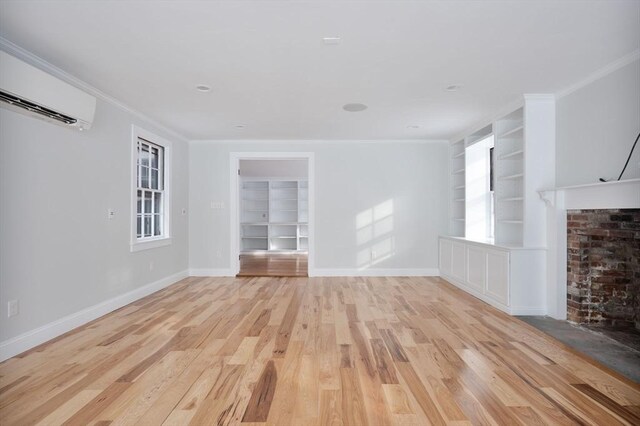 unfurnished living room featuring built in shelves, light hardwood / wood-style flooring, crown molding, and a wall unit AC