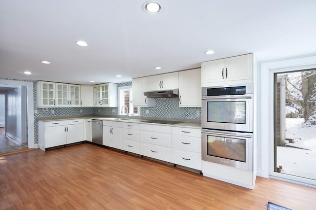 kitchen with sink, white cabinets, light hardwood / wood-style floors, decorative backsplash, and stainless steel appliances