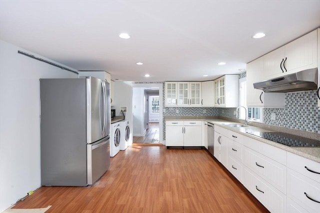 kitchen featuring washing machine and clothes dryer, white cabinets, light wood-type flooring, and appliances with stainless steel finishes