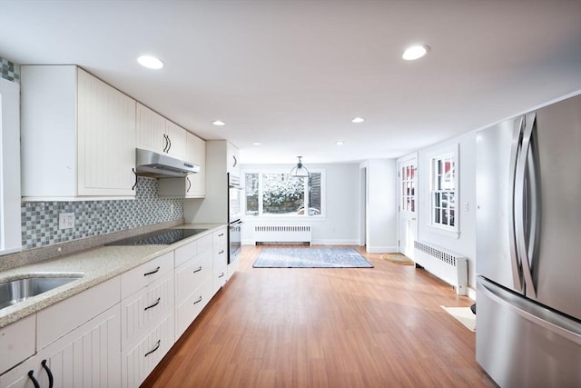 kitchen with white cabinets, stainless steel appliances, and radiator