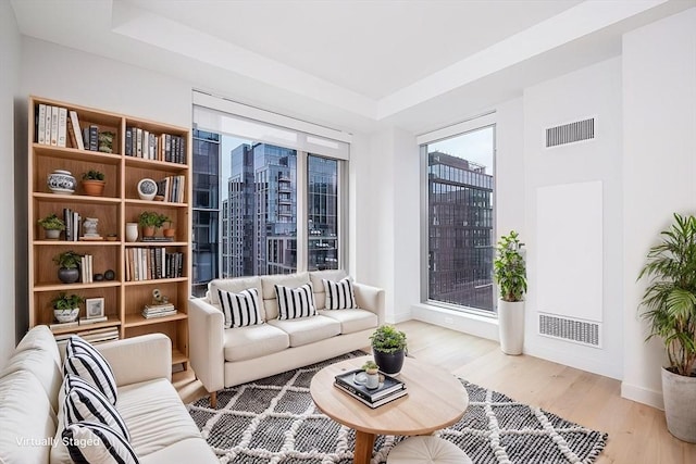 living room with light wood-style flooring, baseboards, and visible vents