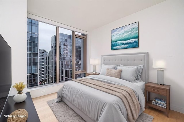 bedroom with a view of city and wood finished floors