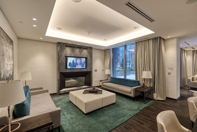 living room with visible vents, a tray ceiling, wood finished floors, recessed lighting, and a fireplace