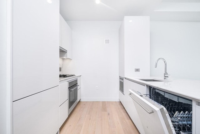 kitchen featuring a sink, light countertops, white cabinets, light wood-style floors, and modern cabinets