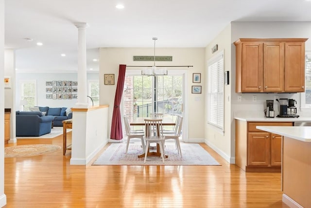 kitchen with decorative columns, light wood-style flooring, light countertops, baseboards, and brown cabinetry