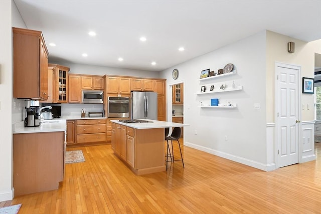 kitchen with appliances with stainless steel finishes, a center island, light wood-style floors, light countertops, and a kitchen breakfast bar