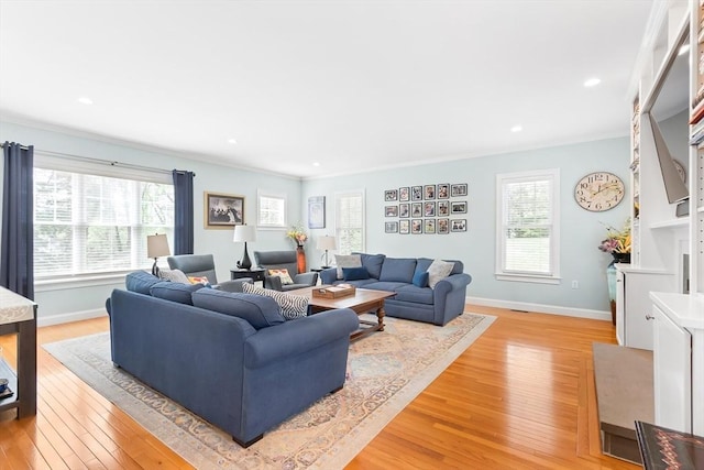 living room featuring plenty of natural light, light wood-type flooring, ornamental molding, baseboards, and recessed lighting