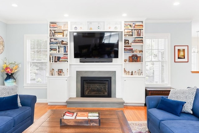 living room featuring wood finished floors, recessed lighting, a premium fireplace, and crown molding