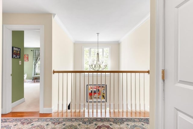 corridor with a chandelier, crown molding, wood finished floors, and baseboards